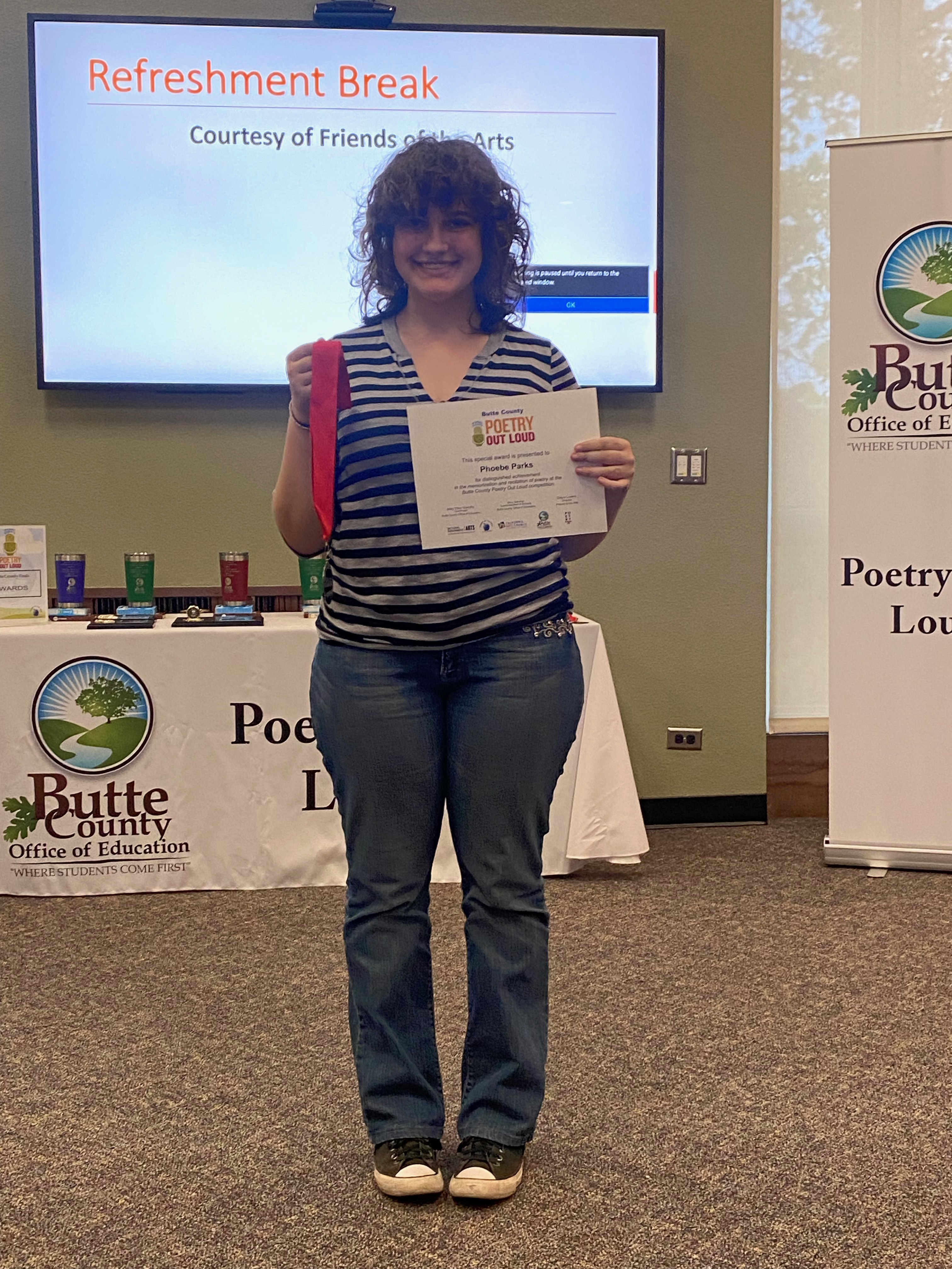 Student Phoebe Parks holding up winning Poetry Out Loud medal and certificate 