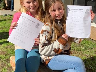 Two Students holding up "Great Kindness Challenge" paper smiling for picture.
