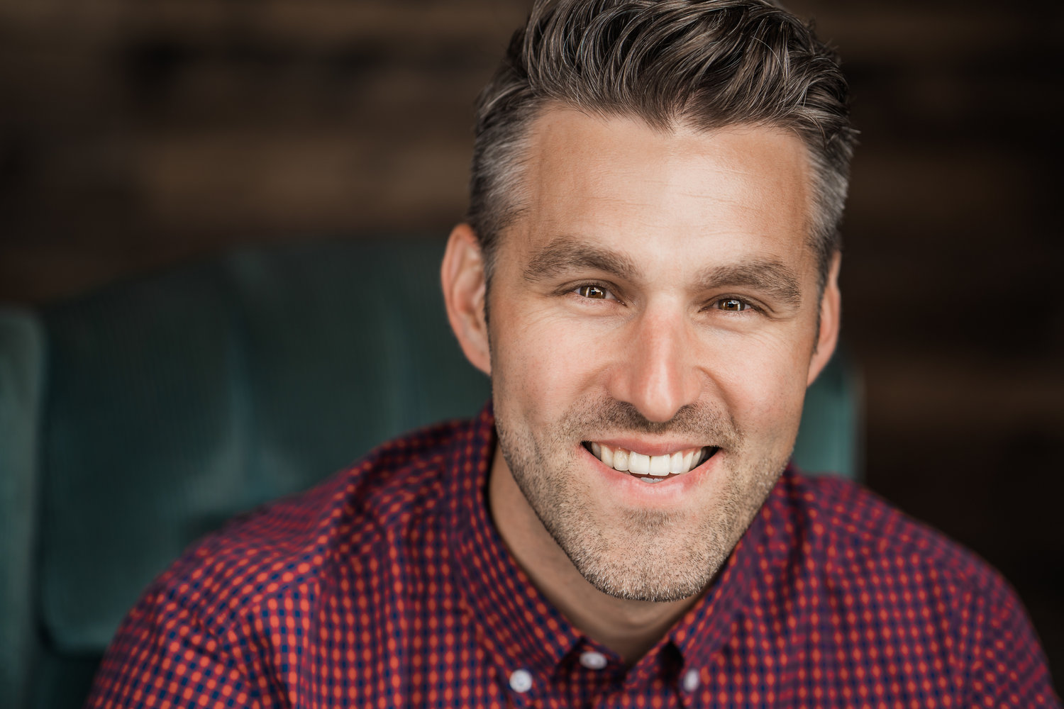 A picture of a man in a red collared shirt, smiling. 